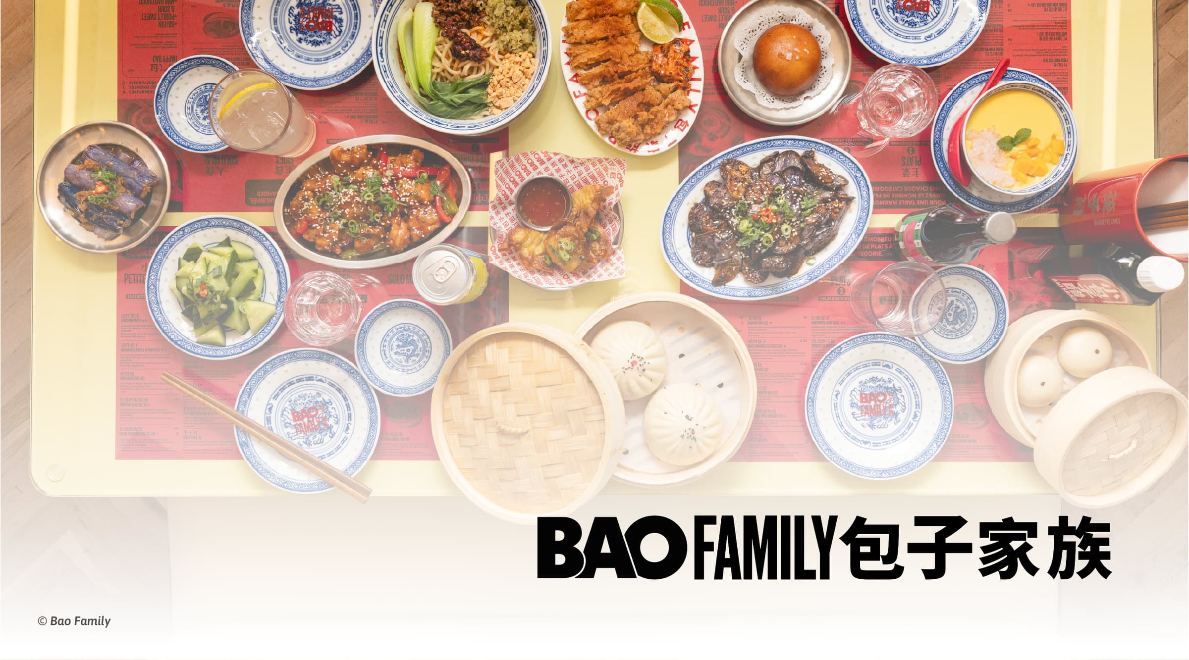 Plats servis chez Bao Family sur une table de restaurant : aubergines, concombres, riz et bao vapeur, avec le logo Bao Family